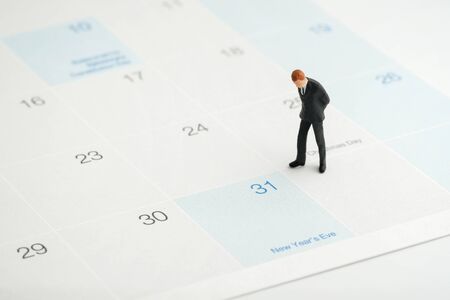 Miniature people : Businessmen standing on the white calendar and look at the end of new year (31...