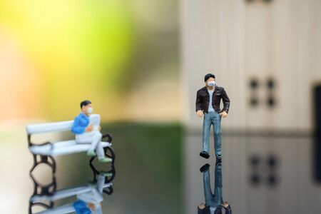 Miniature people : A man who wear mask to protect pollution, corona virus (COVID-19) sitting on the...