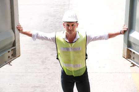 Inspector worker who wears a safety helmet and vest opens the container and checking the quality of cargo. Unload and loading product and transfer to the warehouse. Industrial and logistic concept.の写真素材