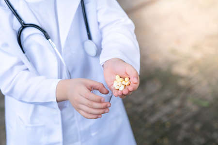 Asia boy wearing a medical suite and place doctor stethoscope on his neck. A boy pouring some drugs...