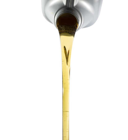 Pouring fresh automotive engine oil (lubricating oil, yellow liquid oil) into a motor car isolated on white background. Change new oil. Maintenance, service, and energy fuel concept.の写真素材
