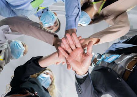 Bottom view of a group of businessmen and women wear a mask and take hand coordination in the...