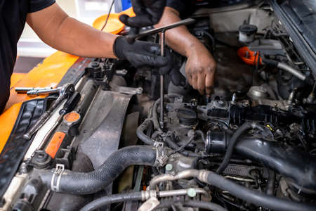 Diesel engine during service, or maintenance at the garage. The internal design of the old engine. Mechanical guy using a screwdriver to remove nuts from the engine box. Engine car spare partの写真素材