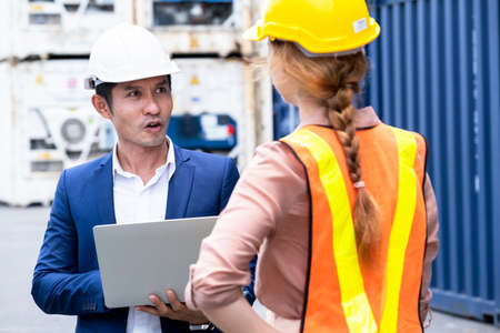 Businessman wearing a safety helmet and holding a laptop and talk with engineer worker woman....