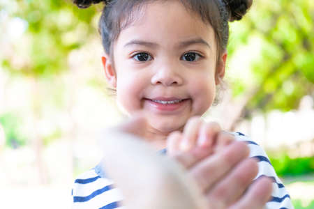 Extreme close up portrait of an adorable cute little girl. Funny kid with the big eyes in the garden. Happy beautiful kid looking at the camera with blurred background. Relax and holiday concept.の写真素材