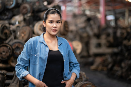 Confident engineer woman workers standing in the automotive spare parts warehouse and smile with factory blurred background. Looking forward. Warehouse and distributor concept.の写真素材