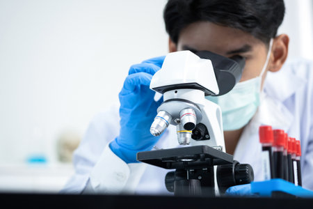 Young scientists wear gloves using a microscope to see coronavirus (Covid-19) in a laboratory. Looking cell virus von plate. Researchers find a vaccine to prevent the virus. Health, medicine conceptの写真素材