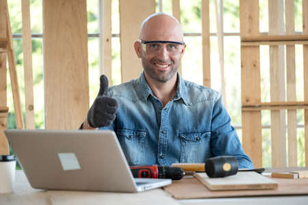 Confident senior craftsman carpenter wearing goggle and glove in the wood workplace. Looking forward...