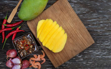 Raw green mango slice with sweet fish sauce on the wooden plate with copy space. Special ingredient, red chili, onion, shrimp, fish sauce, sugar and shrimp paste. Thailand fruit season.  Asia styleの写真素材