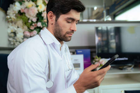 Confident doctor wearing lab coat and stethoscope sitting on sofa at the modern beauty clinic....