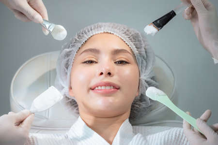 Several beauticians hand holding respective equipment in front of beauty woman face in the clinic or...