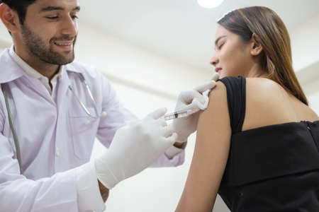 Professional doctor is vaccinations to patients. Man wearing lab coat and inject vaccine from...