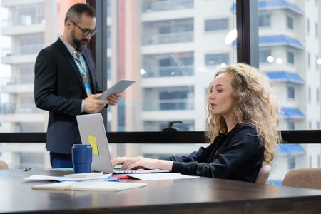 Business woman sitting on the chair and using laptop to see information from internet in the modern...