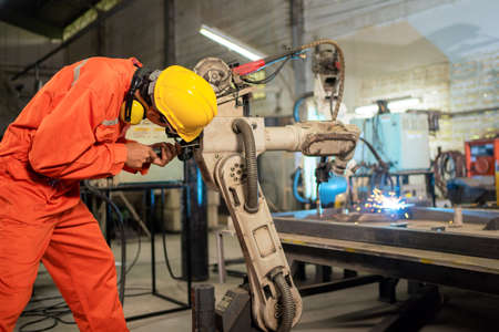Engineer worker repair the arm robot machine. Preventive maintenance in factory. Using screwdriver...