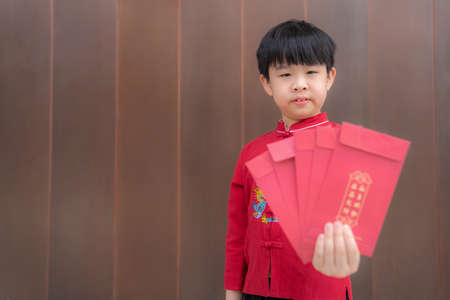 Portrait of Asia boy wearing red shirt and smile during Chinese New Year festival with blur...