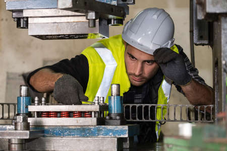 Engineer man wearing safety helmet and vest maintenance or repairing the machine by using wrench in the CNC metal factory. Checking equipment before start production. Industrial and inspectorの写真素材
