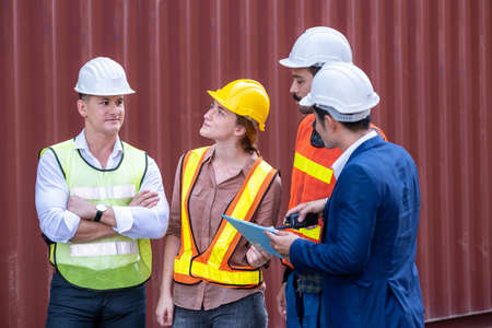 Group of engineer worker standing in the container warehouse. Teamwork and determination to...