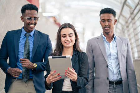 Group of business people standing and discussing on the new project at the walkway city space building. Sharing the idea together. Woman holding tablet and see information. Business and financial.の写真素材