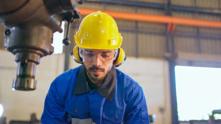 Factory engineer checking or maintenance machine. Wearing safety helmet and glasses to prevent accident. Worker inspector equipment and repair. Industrial, inspector and technology concept.の写真素材