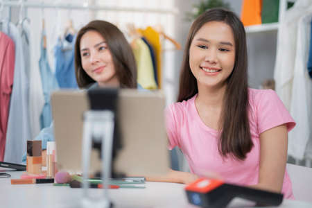 Young Asia woman workin online e-commerce shopping at home. Startup online cosmetic business. Live streaming by using mobile phone video call show product to customer. Buy and sell conceptの写真素材