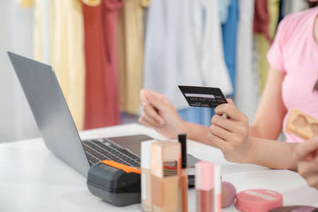 Young woman hand holding credit card and using laptop computer to do shopping online at home....