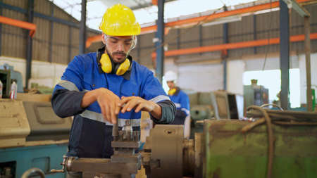 Factory engineer checking or maintenance machine. Wearing safety helmet and glasses to prevent...