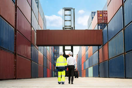 Dock manager and engineer worker discuss on quality at container shipping yard during truck lifting cargo box. Import and export product. Manufacturing transportation and global business conceptの写真素材