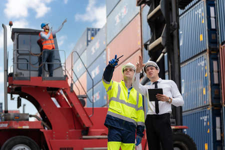 Dock manager and engineer worker point to the container in shipping yard during truck lifting cargo...