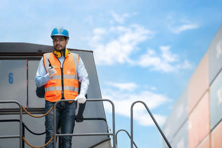 Dock manager man in safety vest holding radio communication and inspector the quality of container...
