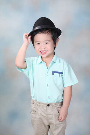 Close up portrait of attractive boy standing in the studio isolated on colorful background with hat. Happy, funny smart boy looking at camera and smile. Lifestyle and pre school conceptの写真素材