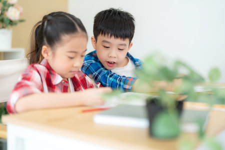 Cute girl and boy sitting in the classroom and doing homework together. Boy looking at friend on her drawing. Portrait of school kid. Learning, education and kindergarten concept. Back to schoolの写真素材
