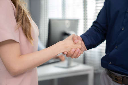 Businesswoman shake hand with businessman in the office room after deal project successful. Happy...