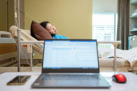 Patient  woman on the bed with saline solution at hospital ward room. Treatment emergency recovery after surgery. Hypertension and hypotension. Healthcare and medical. Husband waiting his wife wake upの写真素材