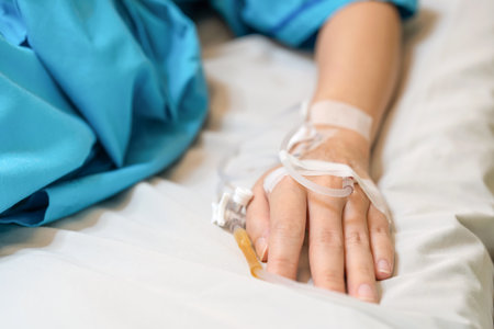 Asia patient woman lying on the bed with saline solution and syringe line on her hand in hospital ward. Emergency and treatment. Healthcare and medical conceptの写真素材