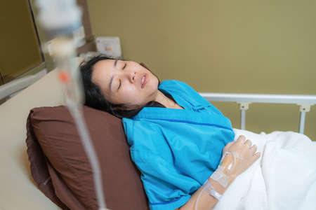 Patient Asia woman on the bed with saline solution and monitor blood pressure at hospital ward room. Treatment emergency recovery after surgery. Hypertension and hypotension. Healthcare and medicalの写真素材