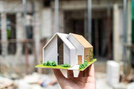 Architect and civil engineer show the house model structure to customer at construction site on sunny day. Renovate and construction concept. Specialists home project. The modern design and ecologyの写真素材
