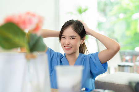 Young Asia pretty doctor sitting at nursing home with smile and collect hair before work. Medical health care worker in blue uniform work at clinic or hospital. Business and medical healthcareの写真素材