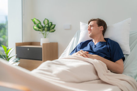 Young caucasian patient lying in bed feeling unhappy and depressed in the hospital. Man with terminal illness resting at hospital ward. Getting sick from long Covid. Medical Treatment and Healthの写真素材