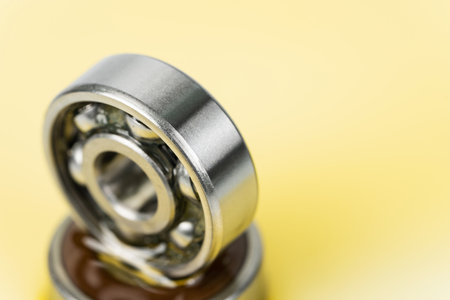 Closed up macro, Pouring automotive engine oil into ball bearing isolated on yellow oil background with copy space, engineering and industrial concept. Motor oil on bearingの写真素材