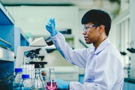 Medical Research Laboratory: Portrait of a asian male Scientist in Goggles Using Micro Pipette for Test Analysis. Advanced Scientific Lab for Medicine, Biotechnology, Microbiology Developmentの写真素材