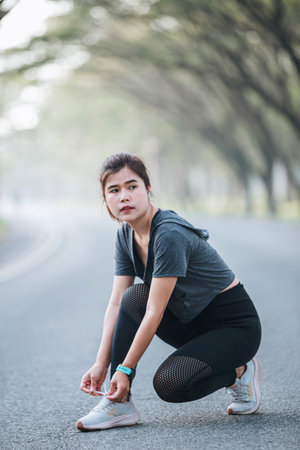 Running shoes - closeup of woman tying shoe laces. Female sport fitness runner getting ready for jogging outdoors on wayの写真素材