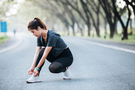 Running shoes - closeup of woman tying shoe laces. Female sport fitness runner getting ready for jogging outdoors on wayの写真素材