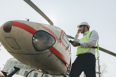 Asian man Aero Engineer Working On Helicopter In Hangar Looking At Digital Tabletの写真素材