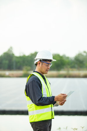 Engineer holding digital tablet with solar panel background in solar power plantの写真素材