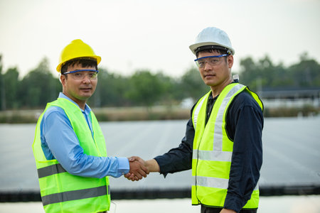 Engineer and Architect shaking hands on the construction site of a solar power plantの写真素材