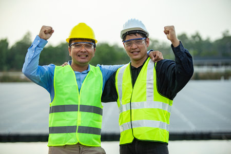 asian engineer and technician wearing safety vests standing in solar power plantの写真素材