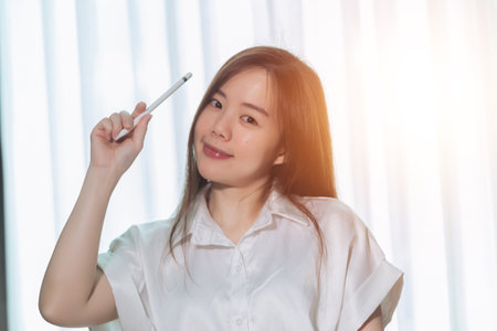 Portrait of young asian businesswoman with pen in office.の写真素材