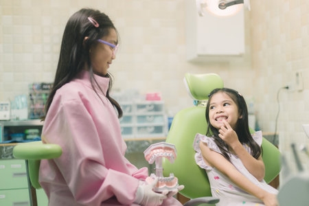 Closeup of the girl touches a crooked milk tooth and experiences pain. Tooth loss, dental problems conceptの写真素材