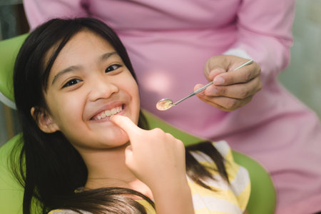 Cute Asain girl touch her teeth during dental treatment at modern clinic.の写真素材