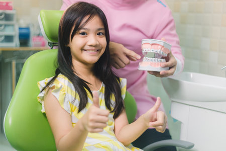 Portrait of happy girl shows thumb up gesture at dental clinicの写真素材